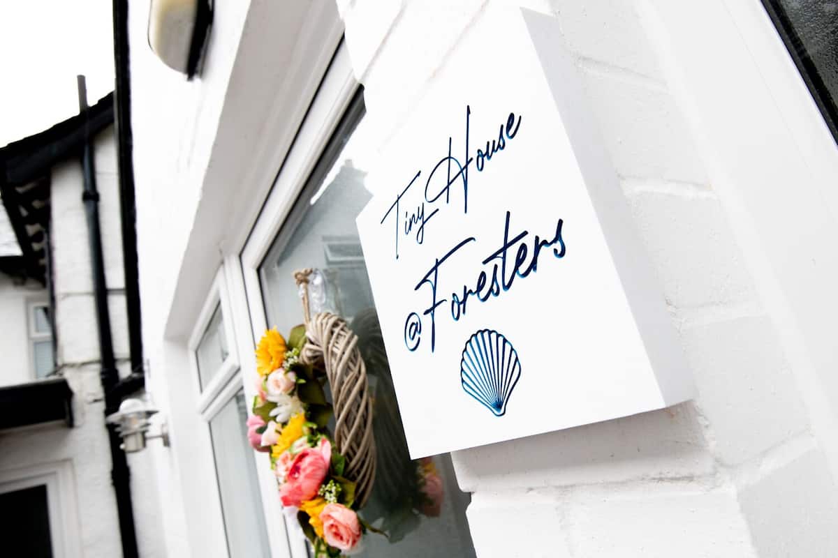 A sign for 'The House of Foresters' with a decorative floral arrangement below it.