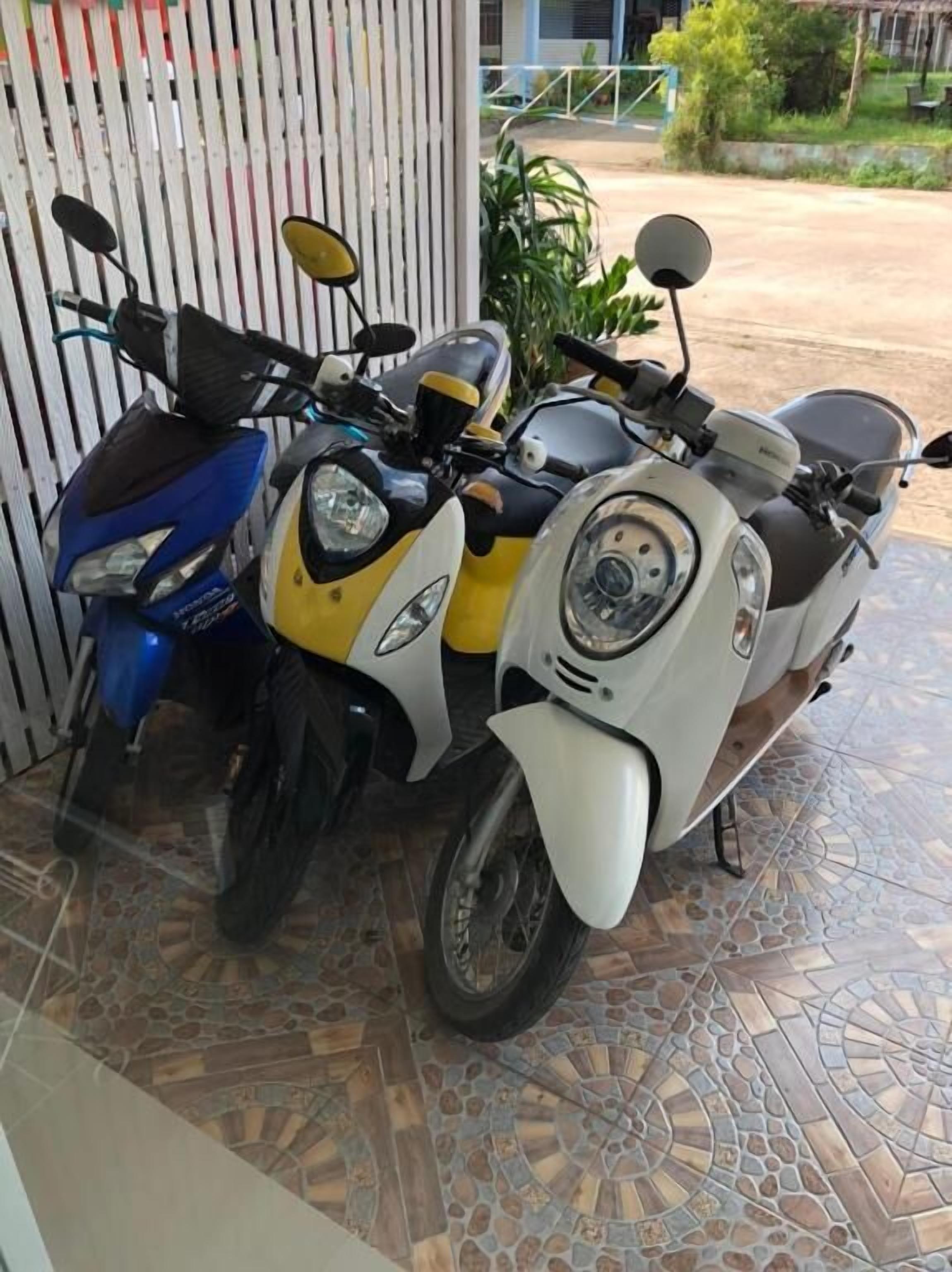 Dos scooters estacionados frente a un edificio con piso de baldosas.