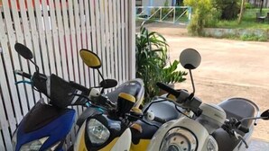 Two scooters parked in front of a building with a tiled floor. - DKaYa Hostel (Takua Pa)