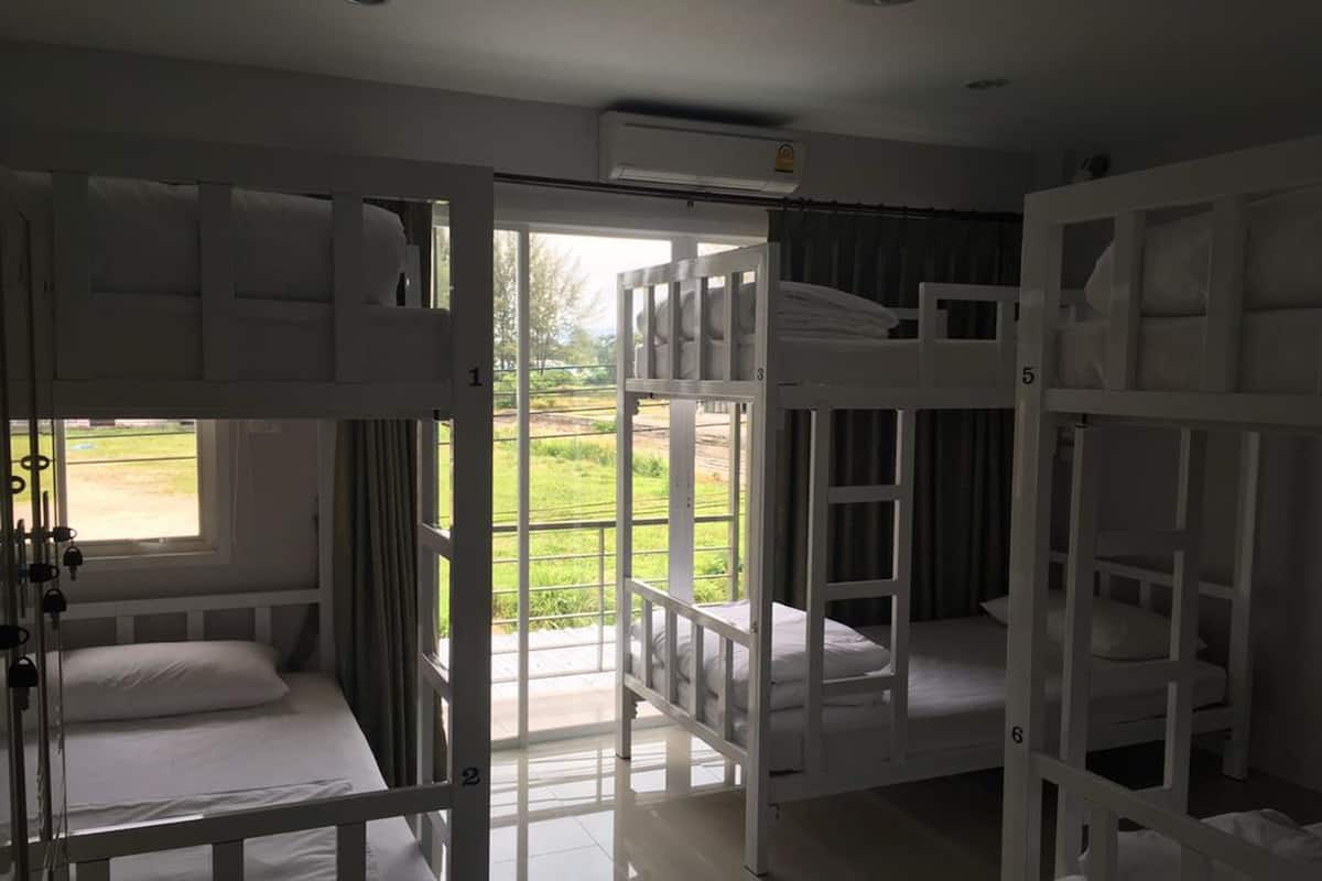 A room with bunk beds, a large window, and an air conditioning unit.