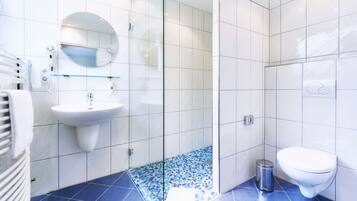 Ein Badezimmer mit Waschbecken, Spiegel, Toilette und Duschbereich.