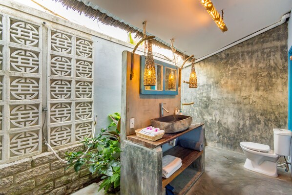 A bathroom with a stone sink, a blue-framed mirror, and a white toilet.