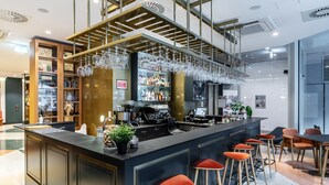 Zona de bar moderna con mostrador, taburetes y una variedad de botellas.