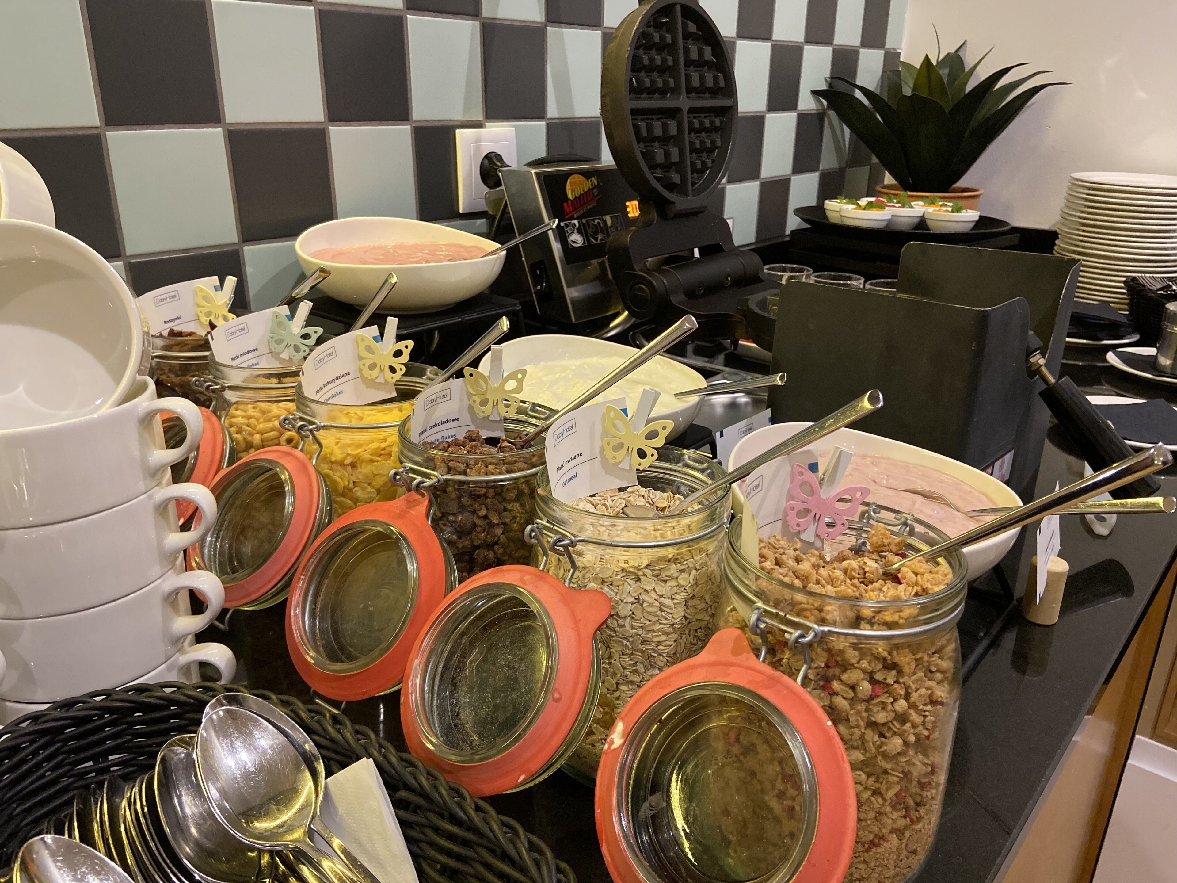 Un buffet avec différents plats présentés dans des bocaux et des bols, ainsi que des ustensiles et un appareil à gaufres.