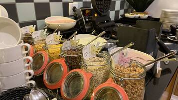 Un buffet avec différents plats présentés dans des bocaux et des bols, ainsi que des ustensiles et un appareil à gaufres.
