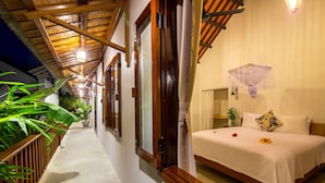 Una habitación de hotel con una cama, mosquitero colgante y techo de madera.