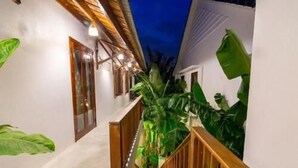 Un estrecho sendero con valla de madera que conduce a un edificio blanco con escaleras.