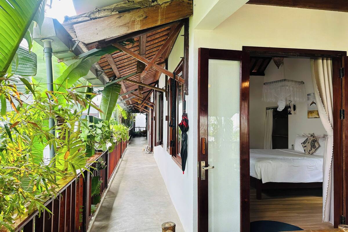 A corridor with a wooden ceiling, a bed with a canopy, and a door leading to a bedroom.