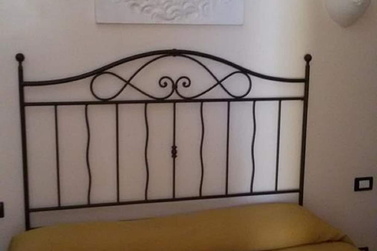 A bed with a metal headboard and a framed artwork above it.