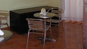A dining area with a table and chairs, a black sofa, and a wall-mounted basket display. - Hotel Bella Napoli (Agrigento)