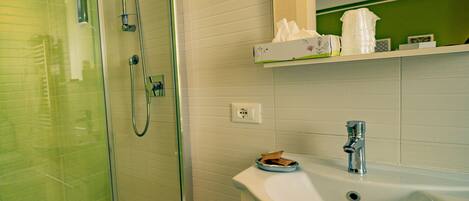 A modern bathroom with a glass-enclosed shower, a white sink, and a mirror above the sink.