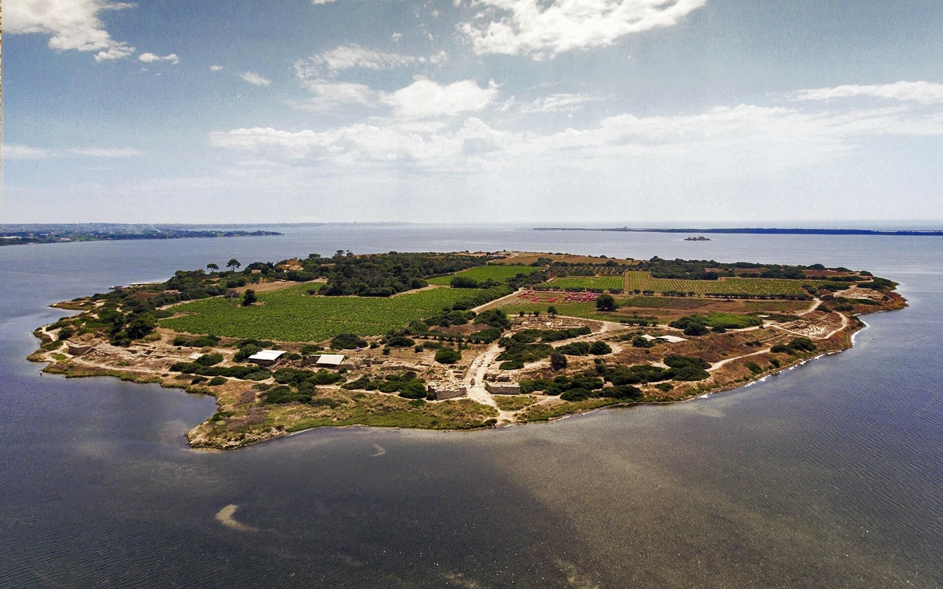 An aerial view of an island with various fields, buildings, and a body of water.