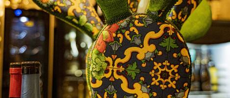 Una escultura de cactus con una maceta estampada, una botella de Horatio y un fondo borroso de estanterías.