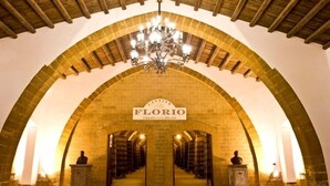 Una entrada arqueada con un candelabro, un letrero que dice 'CANTINE FLORIO' y estatuas en la base.