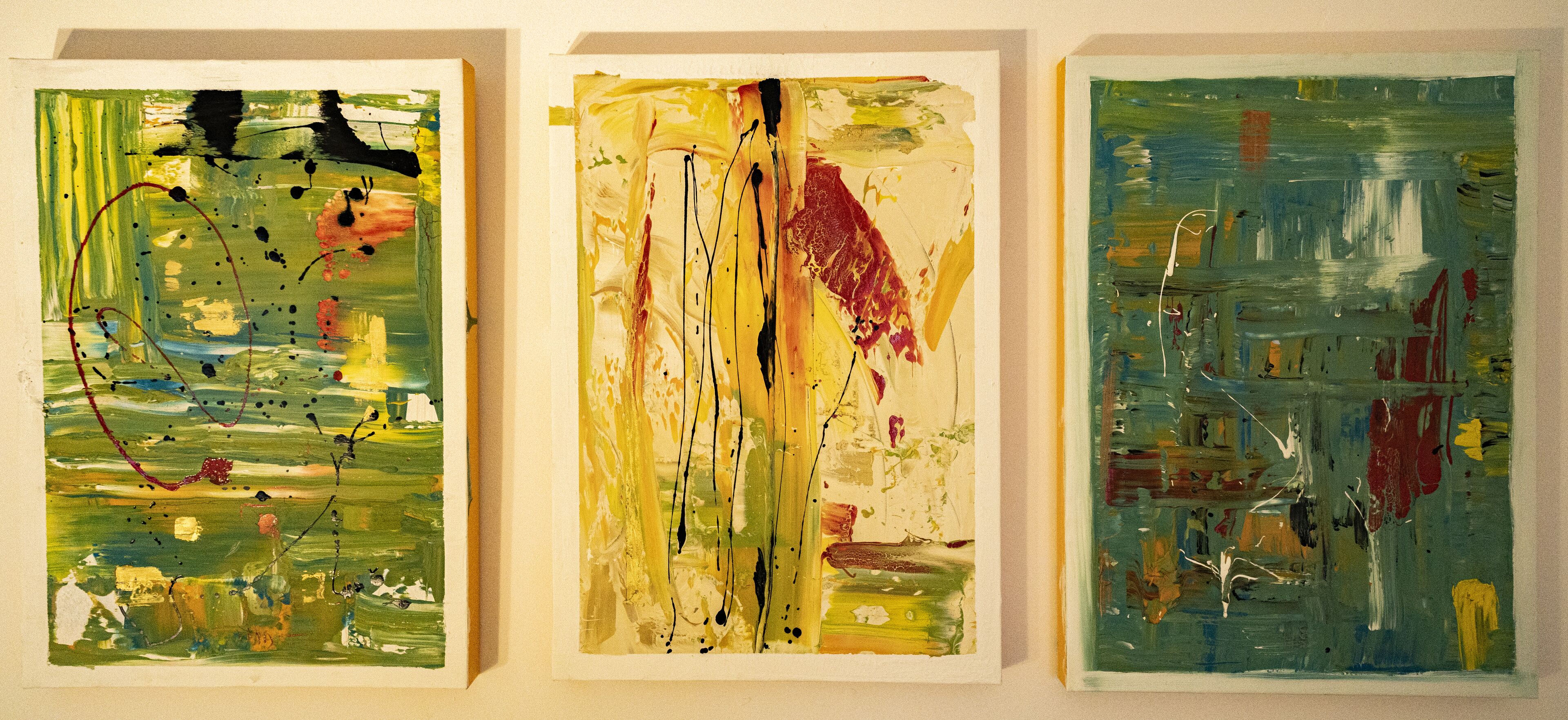 Três pinturas abstratas em uma parede.