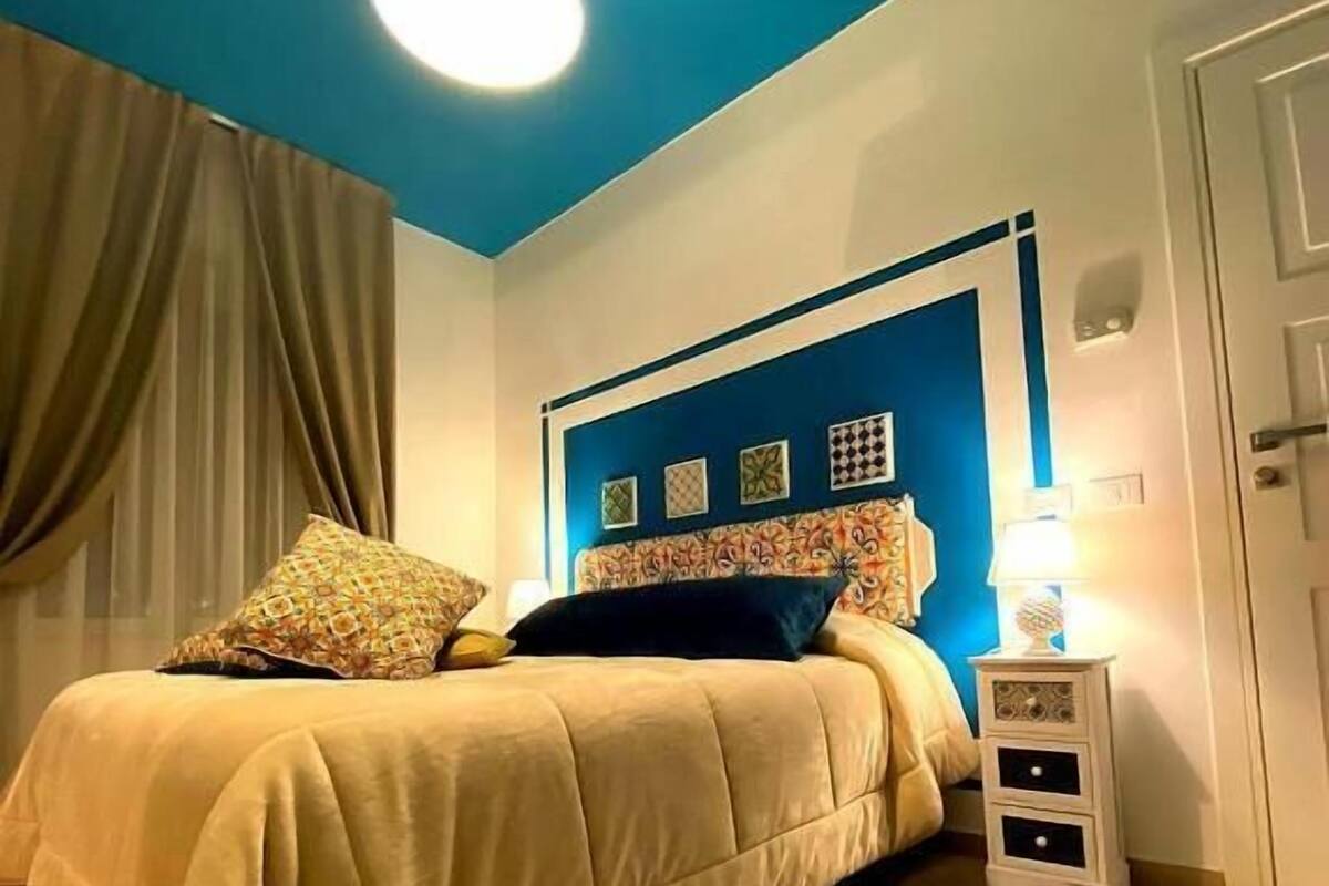 Une chambre à coucher avec un lit, une table de chevet, une lampe et un tapis à motifs.