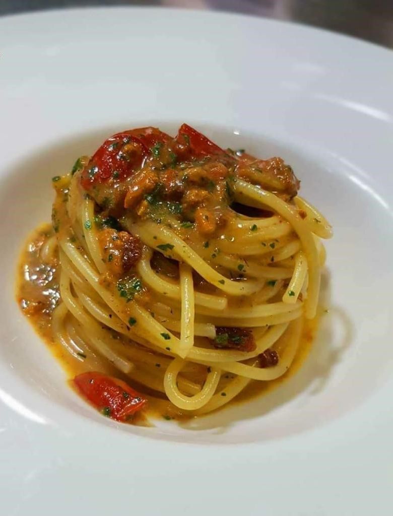 A plate of spaghetti with a tomato-based sauce and herbs.