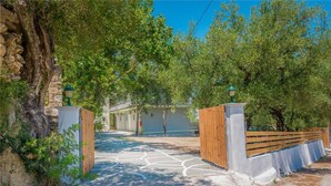 A paved pathway leading to a building with a wooden fence and stone walls. - Blue Lagoon (Zakynthos)