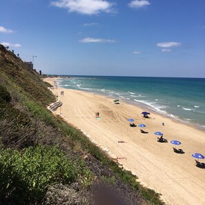 A beach with a sandy shore, a few umbrellas, and a few people. - Medi Terre Boutique Hotel - By Saida Hotels (Netanya)