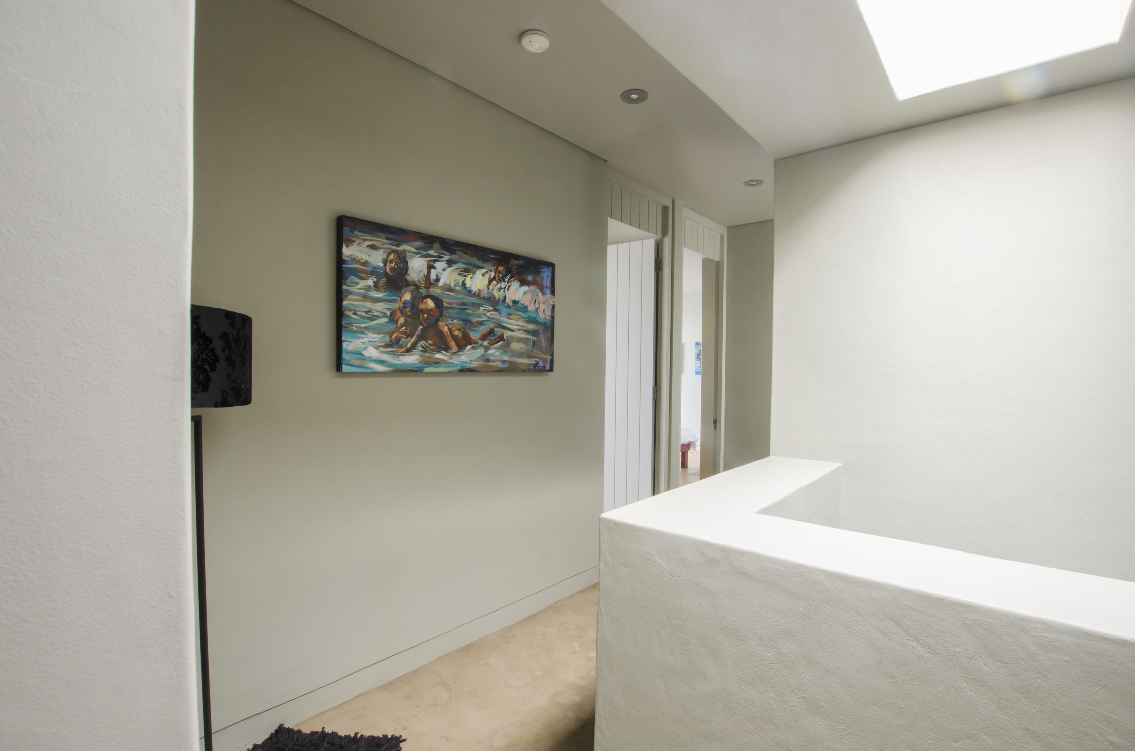 Un pasillo con un cuadro, un mostrador de recepción blanco y una puerta que da a otra habitación.