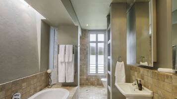 A modern bathroom with a bathtub, sink, and shower area.