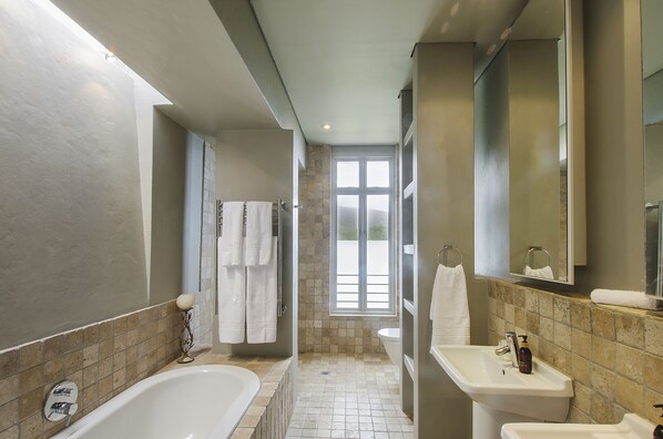 A modern bathroom with a bathtub, sink, and shower area.