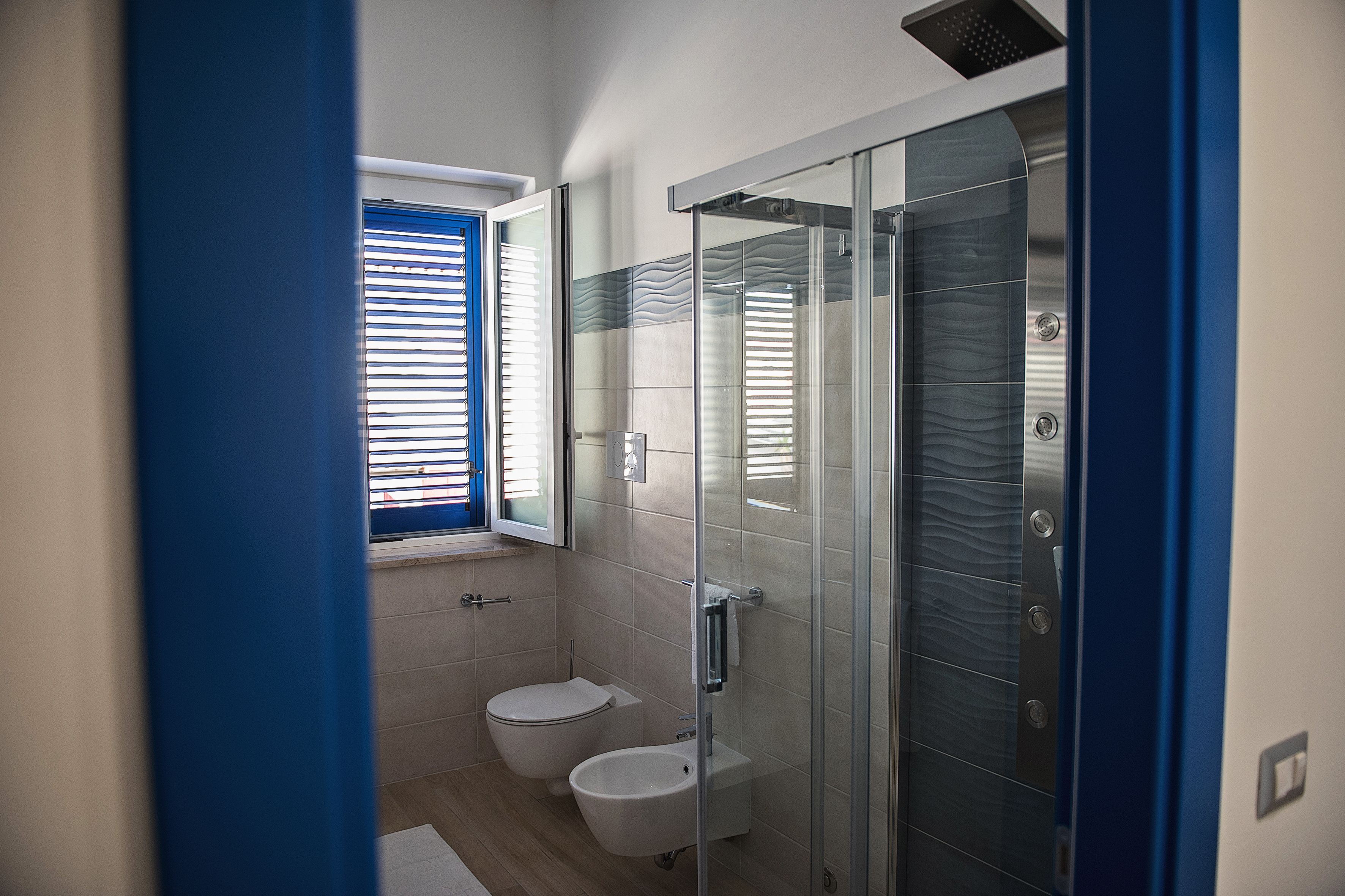 Een moderne badkamer met een glazen douchecabine, toilet en een douchetoilet.