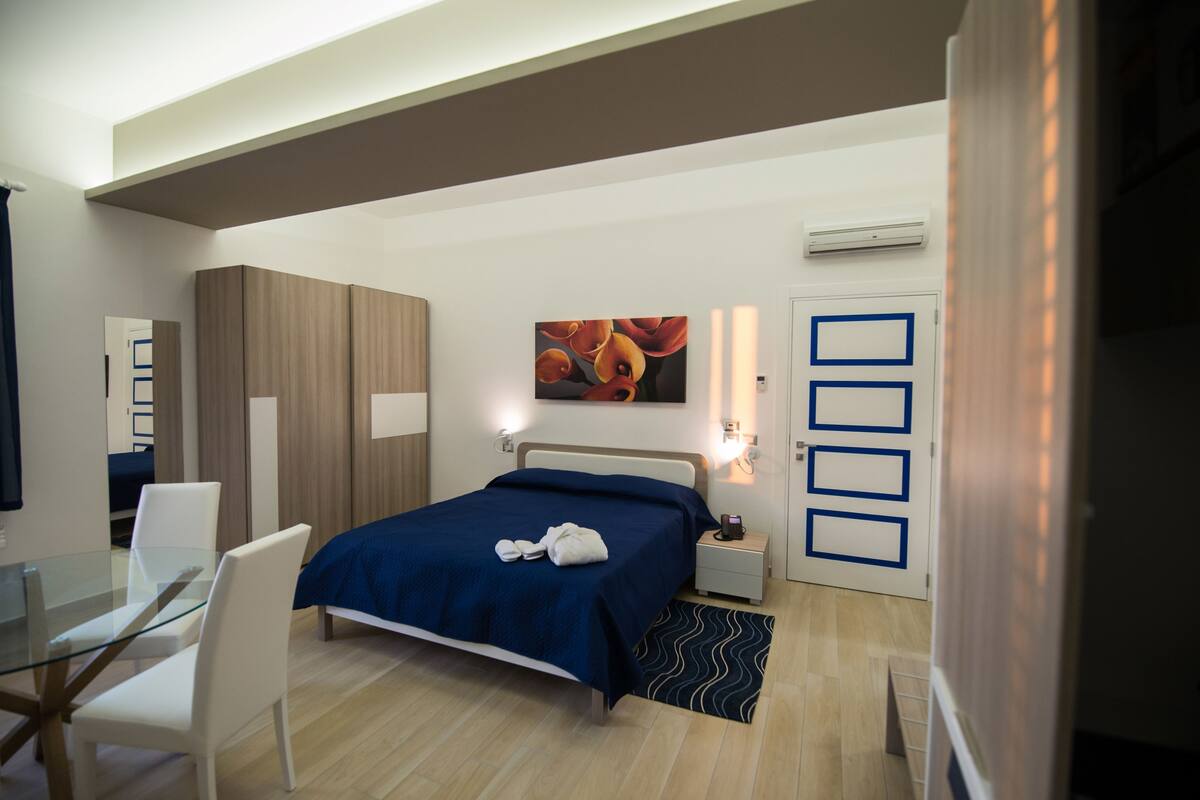 Ein modernes Schlafzimmer mit Bett, Nachttischen, einem Schreibtisch und einem Kleiderschrank.