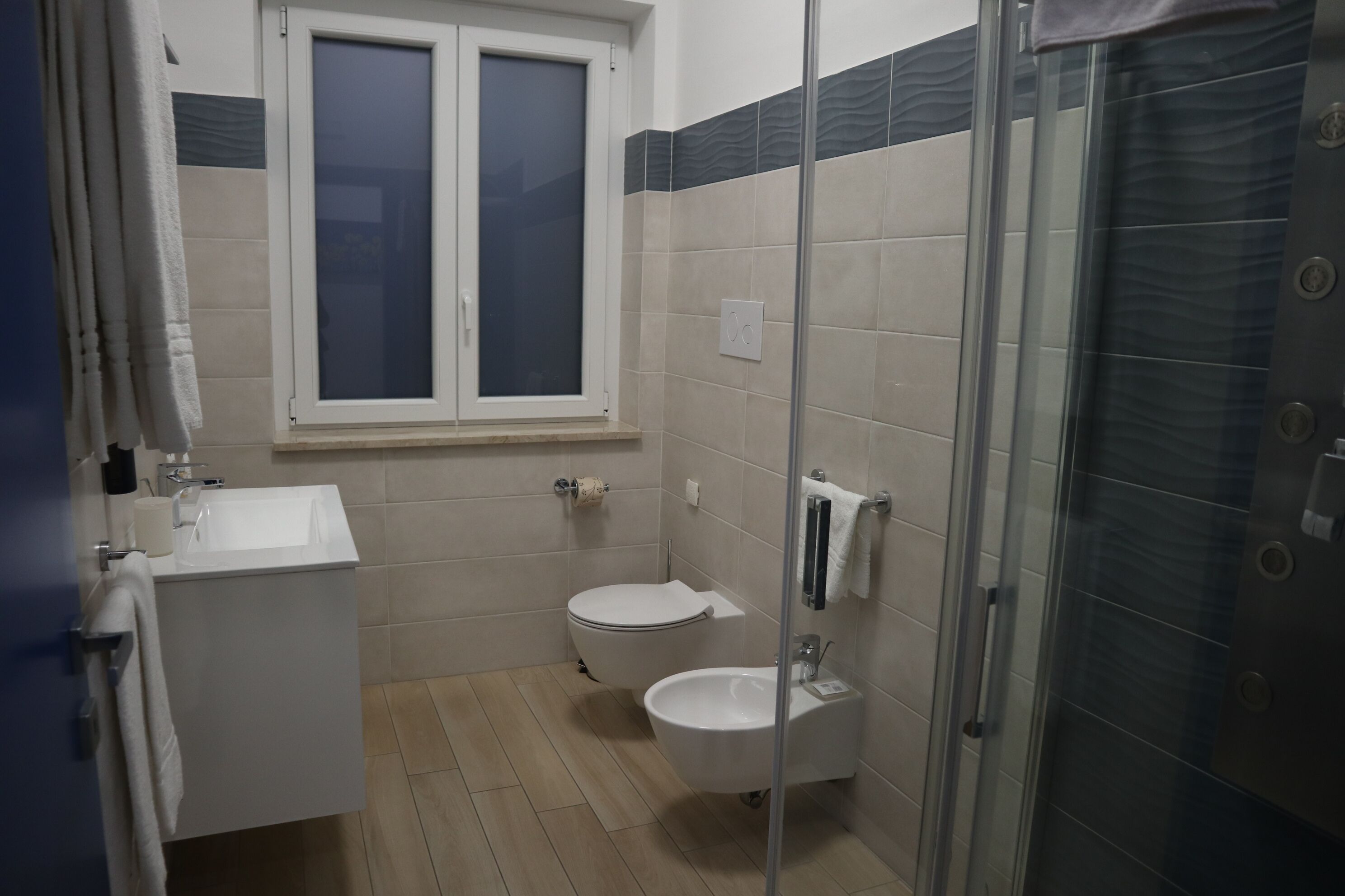 Un baño con lavamanos, inodoro y cabina de ducha de vidrio.