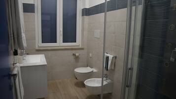 Un baño con lavamanos, inodoro y cabina de ducha de vidrio.