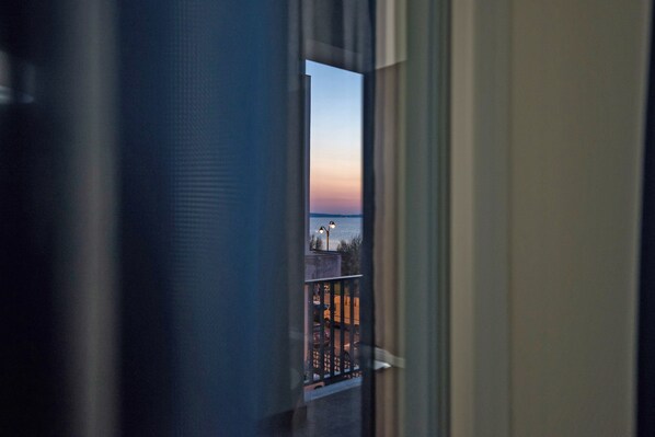A view through a window with a balcony, a railing, and a distant horizon.