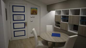 Une pièce moderne avec une table ronde en bois, des chaises blanches, une porte blanche avec des encadrements bleus et des étagères intégrées aux finitions en bois clair.