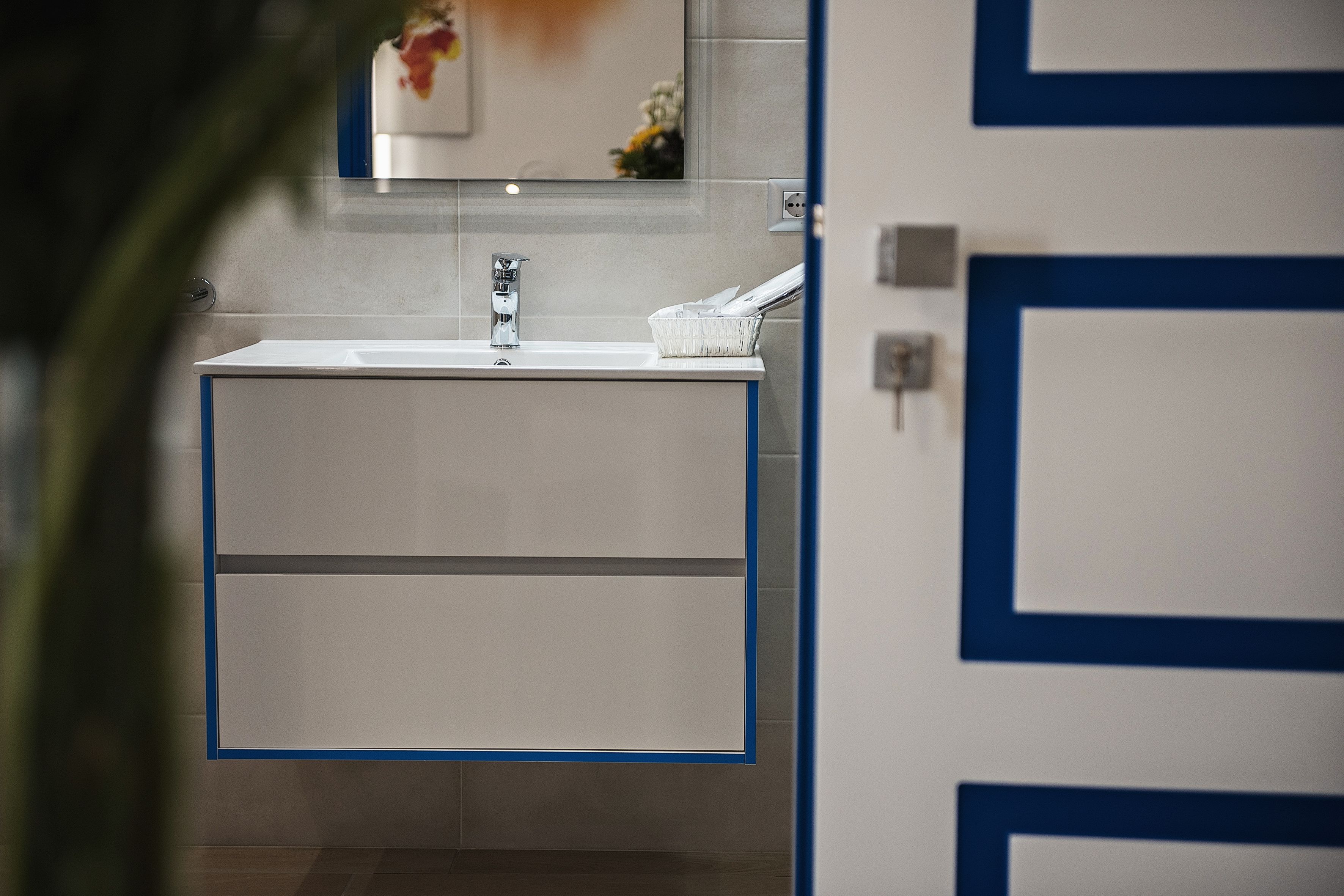 A bathroom with a white sink, mirror, and blue-framed cabinets.