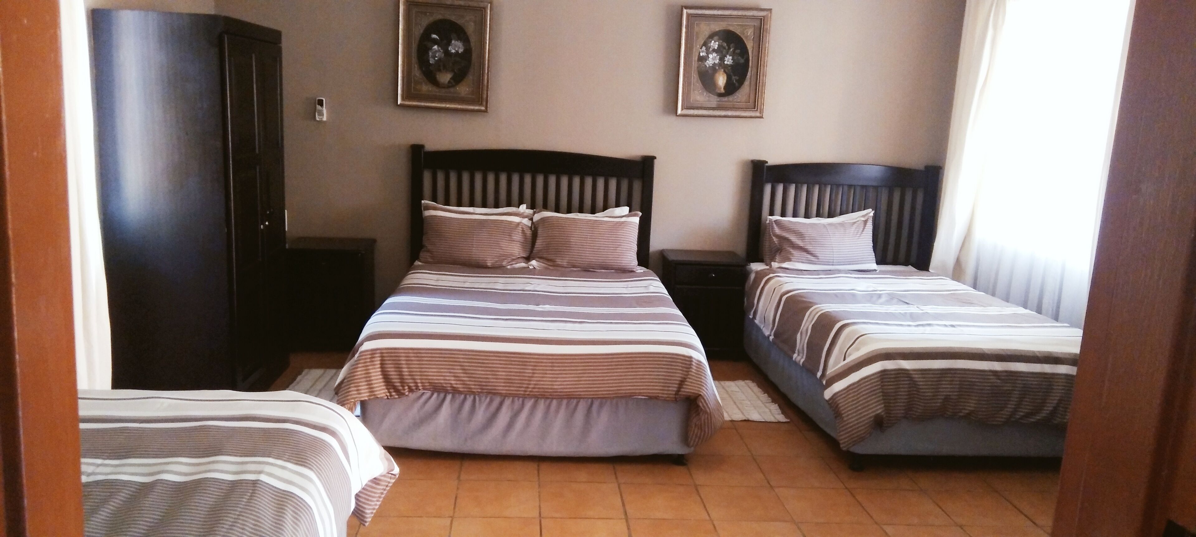 Ein Zimmer mit zwei Betten, einem Kleiderschrank und zwei Nachttischen.