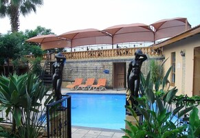 A pool area with lounge chairs, umbrellas, and a statue.