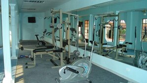 Ein Fitnessraum mit Trainingsgeräten, einem großen Spiegel und einem Fenster mit Blick nach draußen.