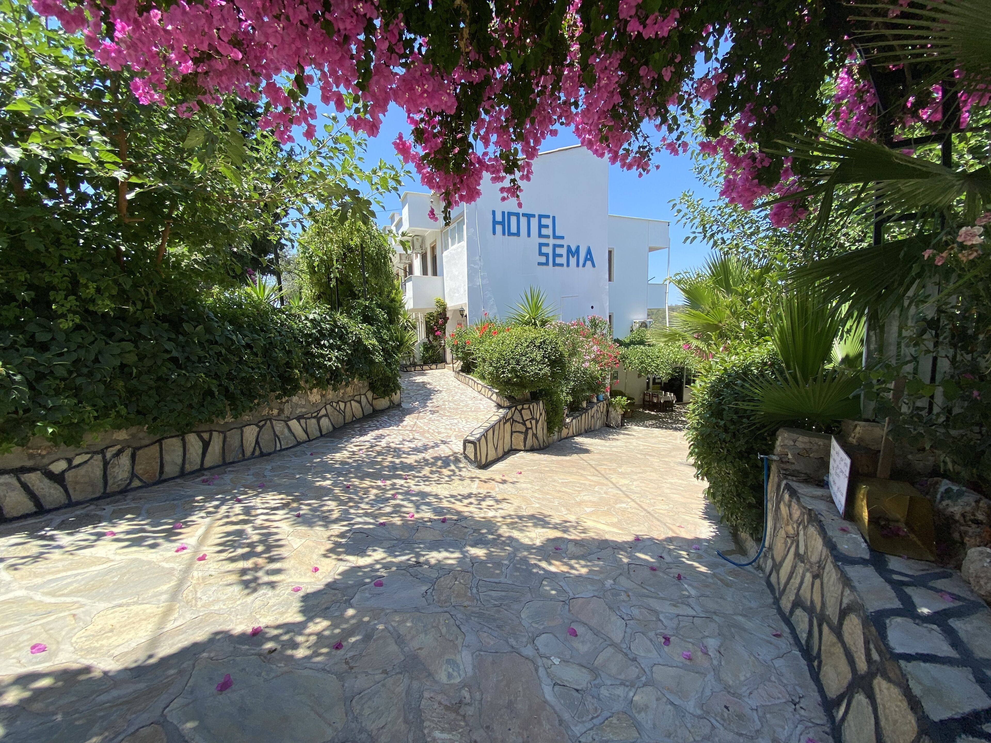 A stone pathway leading to a hotel entrance with a sign reading "HOTEL SEMA".
