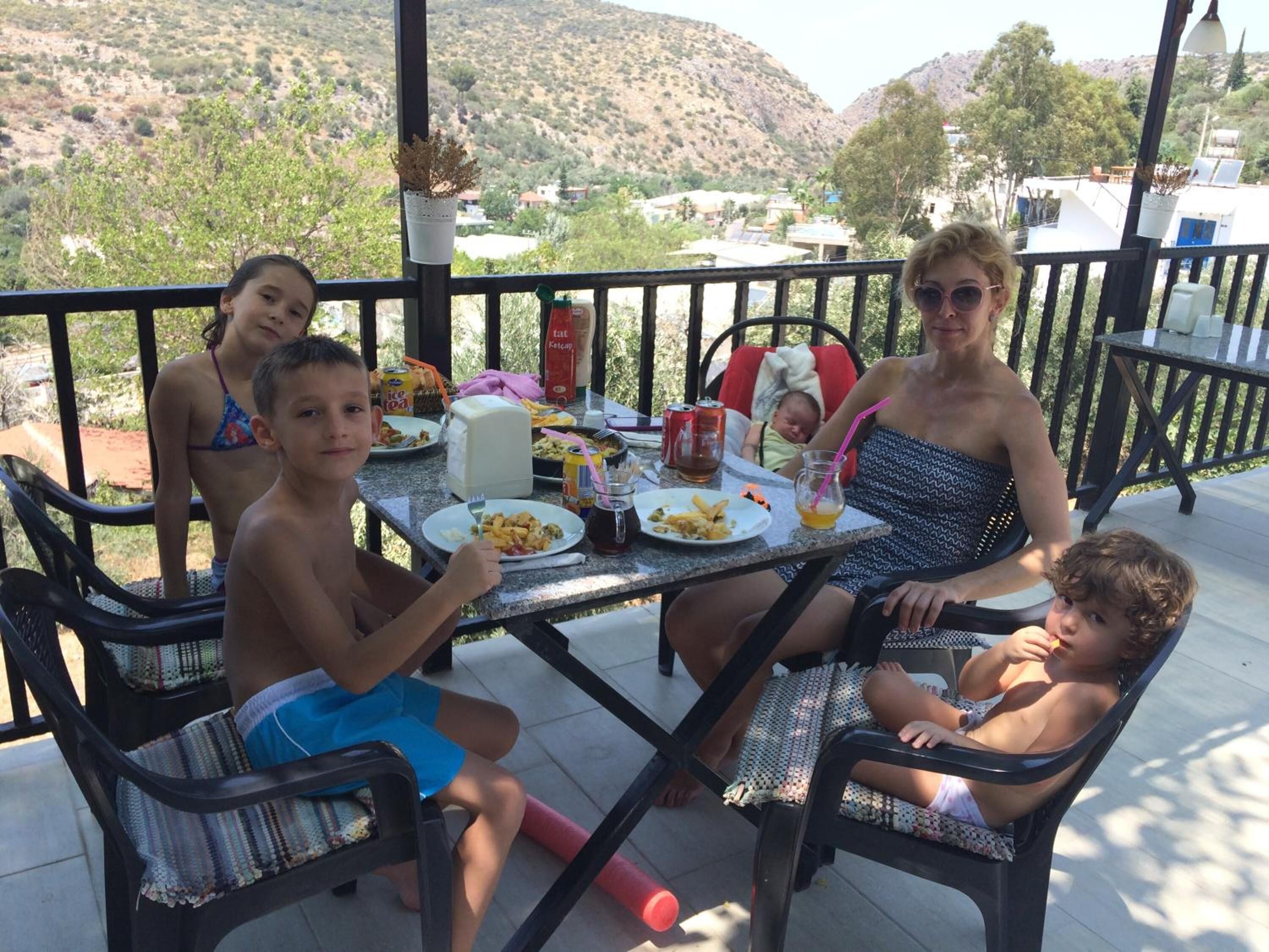 Una familia cenando en un porche cubierto con vistas a un paisaje montañoso.