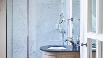 Un baño moderno con ducha de mármol, lavamanos con espejo y armarios de madera.