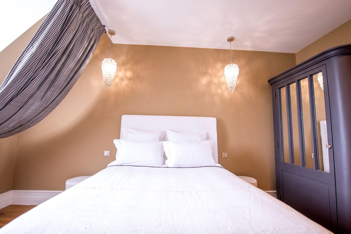 A bedroom with a bed, a dark wooden wardrobe, and two wall-mounted lights.
