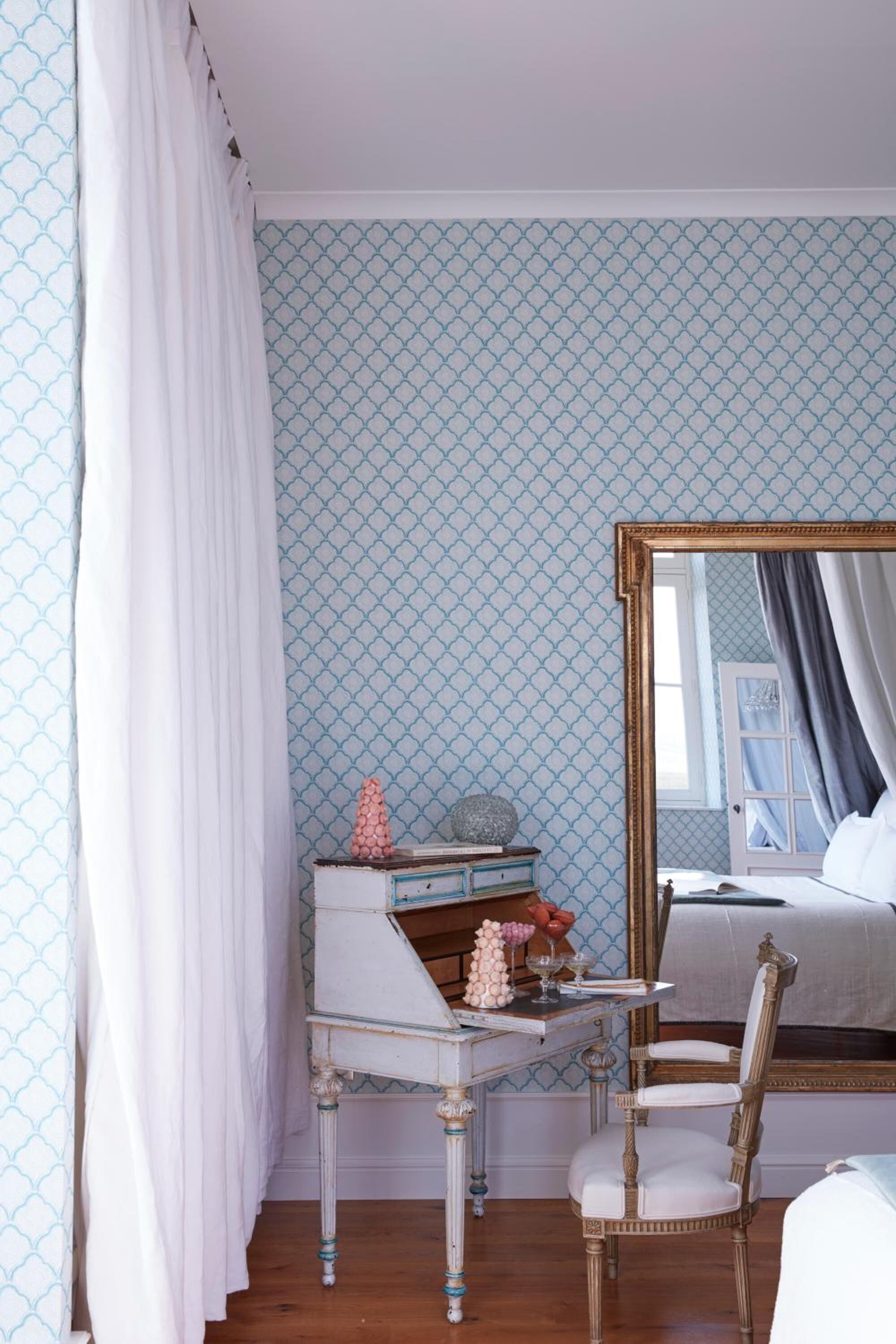 A bedroom with a bed, a mirror, a dresser, and a chair.