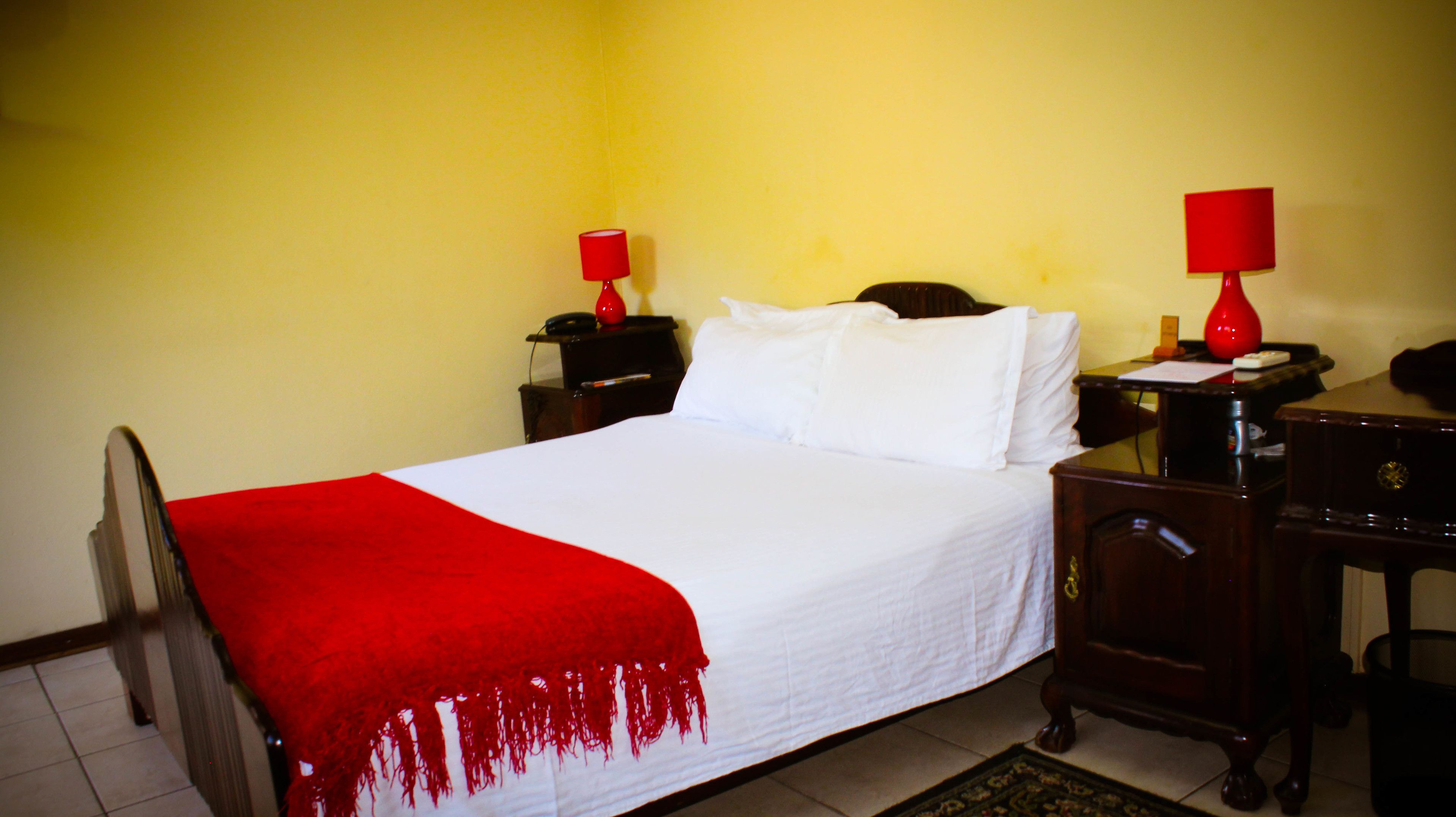 Une chambre d’hôtel comprenant un lit, deux tables de chevet, un bureau et une chaise.
