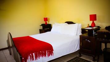 Une chambre d’hôtel comprenant un lit, deux tables de chevet, un bureau et une chaise.
