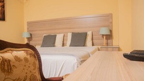 Une chambre d’hôtel avec un lit, deux lampes de chevet, une télécommande et une tête de lit en bois.