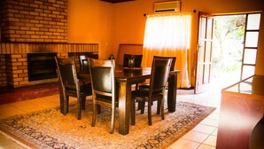 Un coin repas avec une cheminée en briques, une table en bois et des chaises.