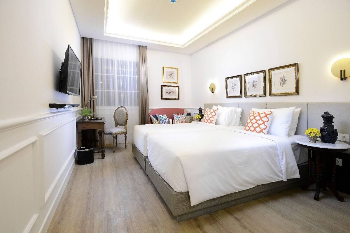 A hotel room with a large bed, a desk, a chair, and a TV.