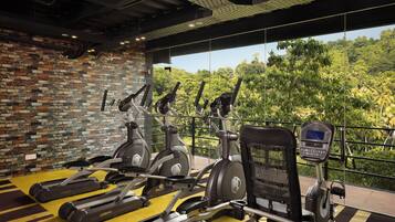 Una palestra con tapis roulant, cyclette e vogatore.