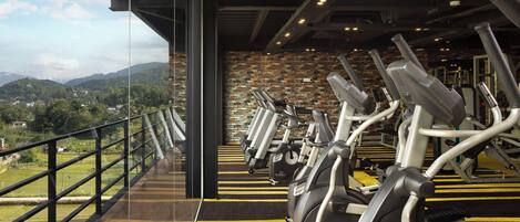 A gym with stationary bikes and a view of a mountainous landscape.
