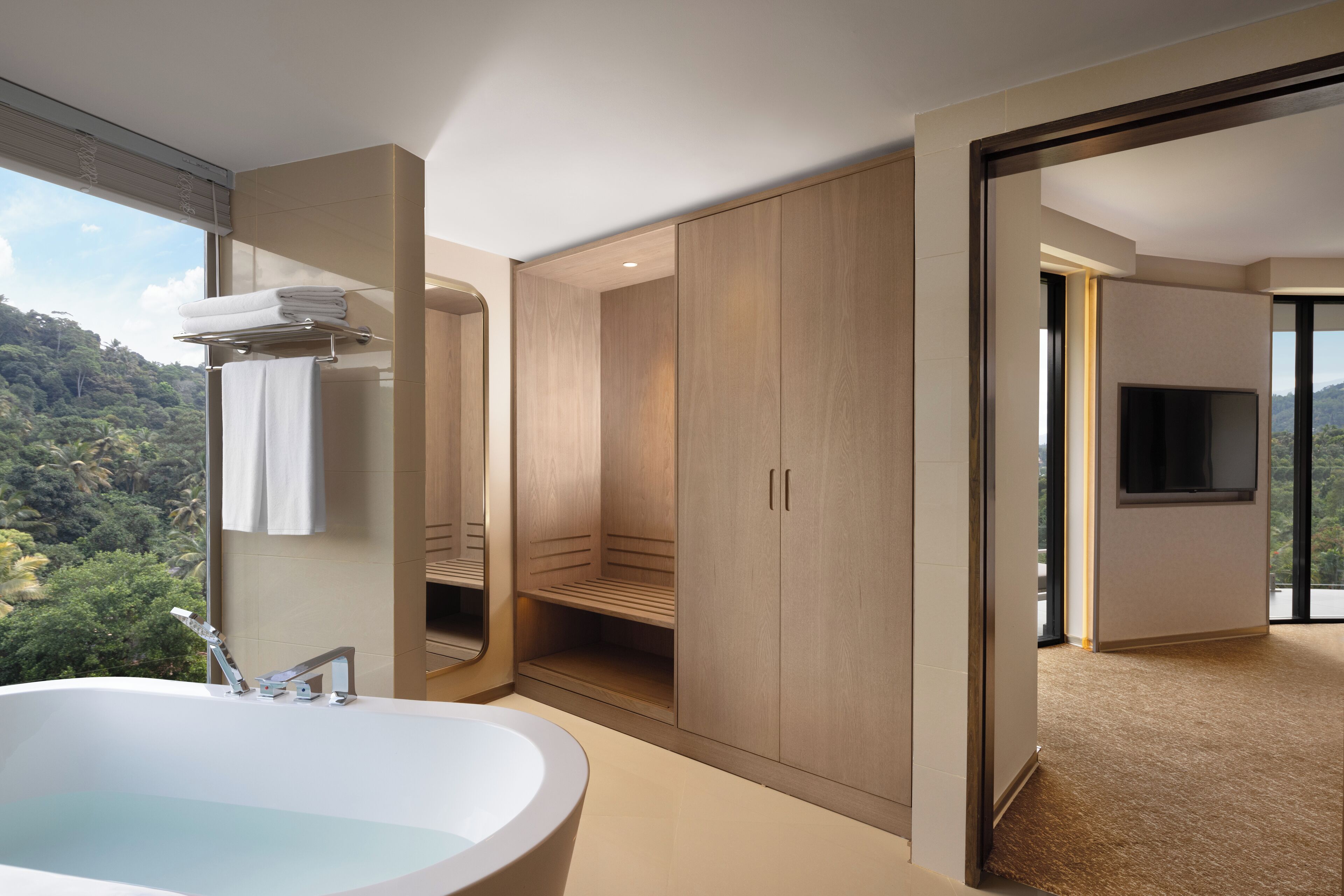 Un baño moderno con una bañera grande, ducha y tocador con espejo. Se ve un paisaje montañoso a través de la ventana.