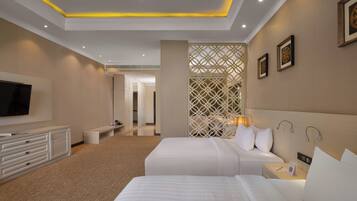 A hotel room with two beds, a TV, a desk, and a decorative partition.
